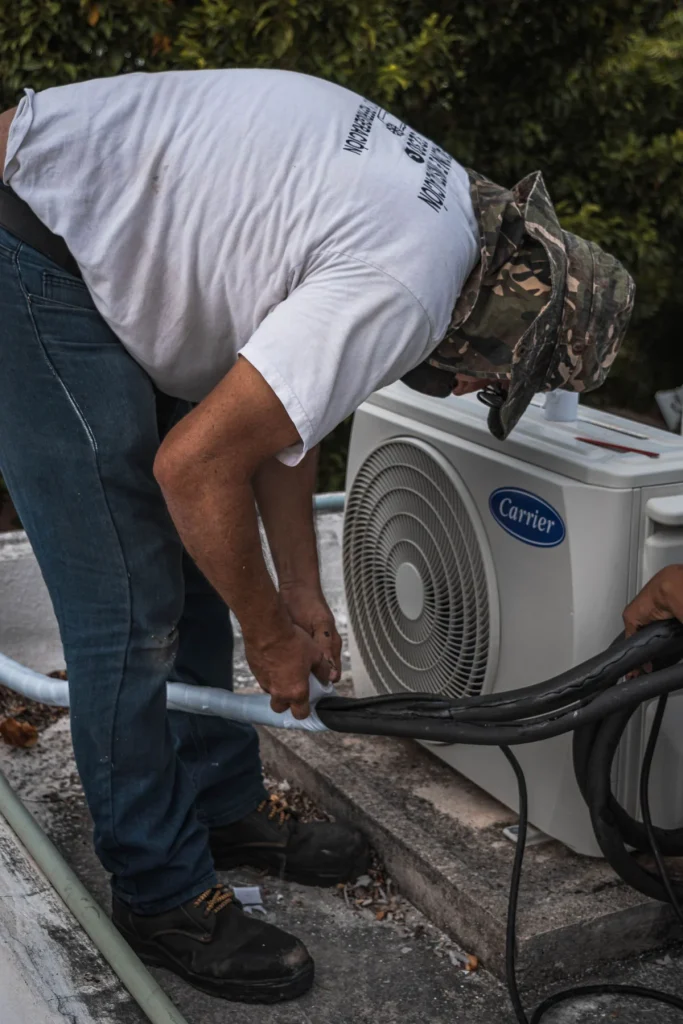 Technician connecting a hose to an outdoor condenser during an AC service call