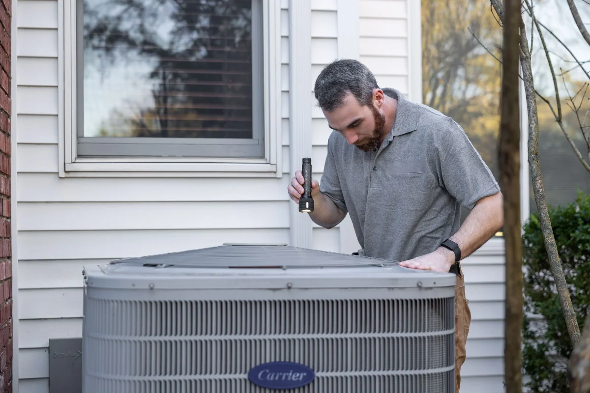 AC repair technician inspecting a residential outdoor air conditioner