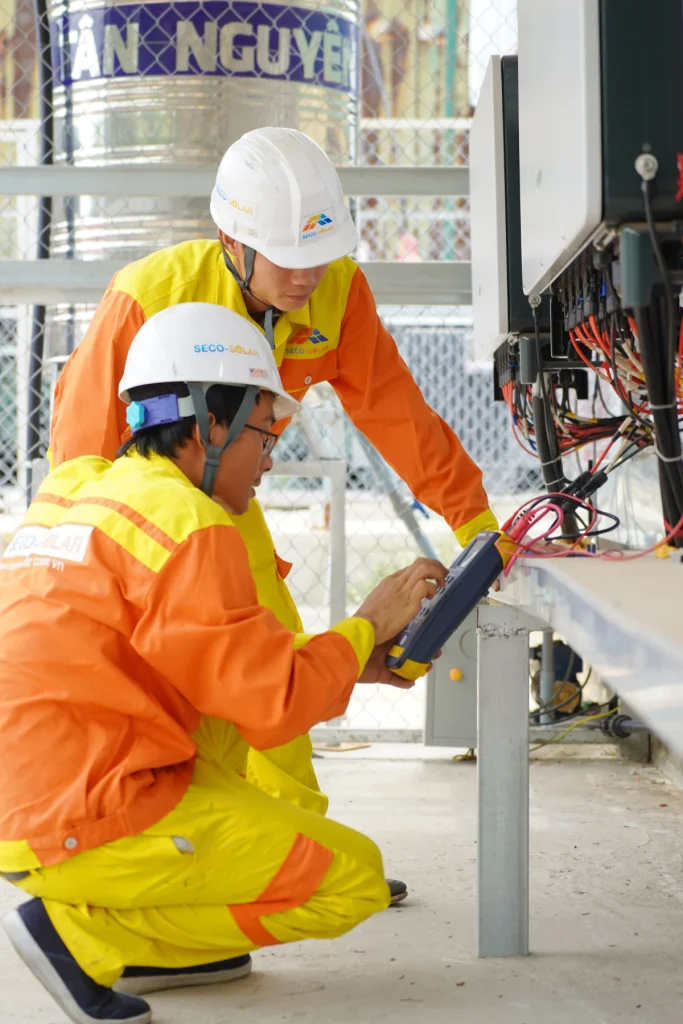 Two maintenance technicians in hard hats and safety vests on a job site