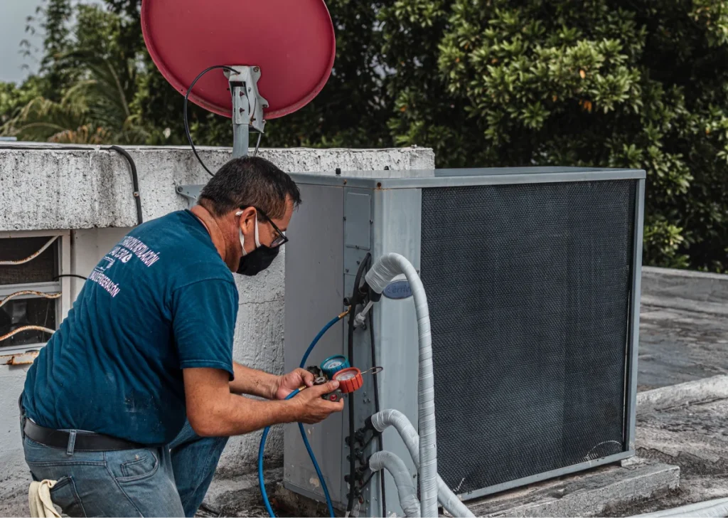 Technician checking refrigerant pressures on a rooftop condenser