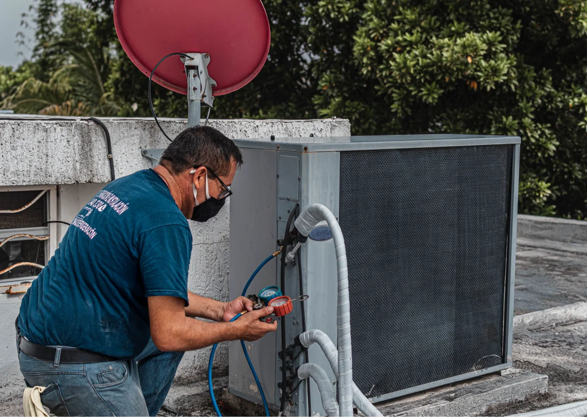 Air conditioning technician checking an outdoor unit with pressure gauges