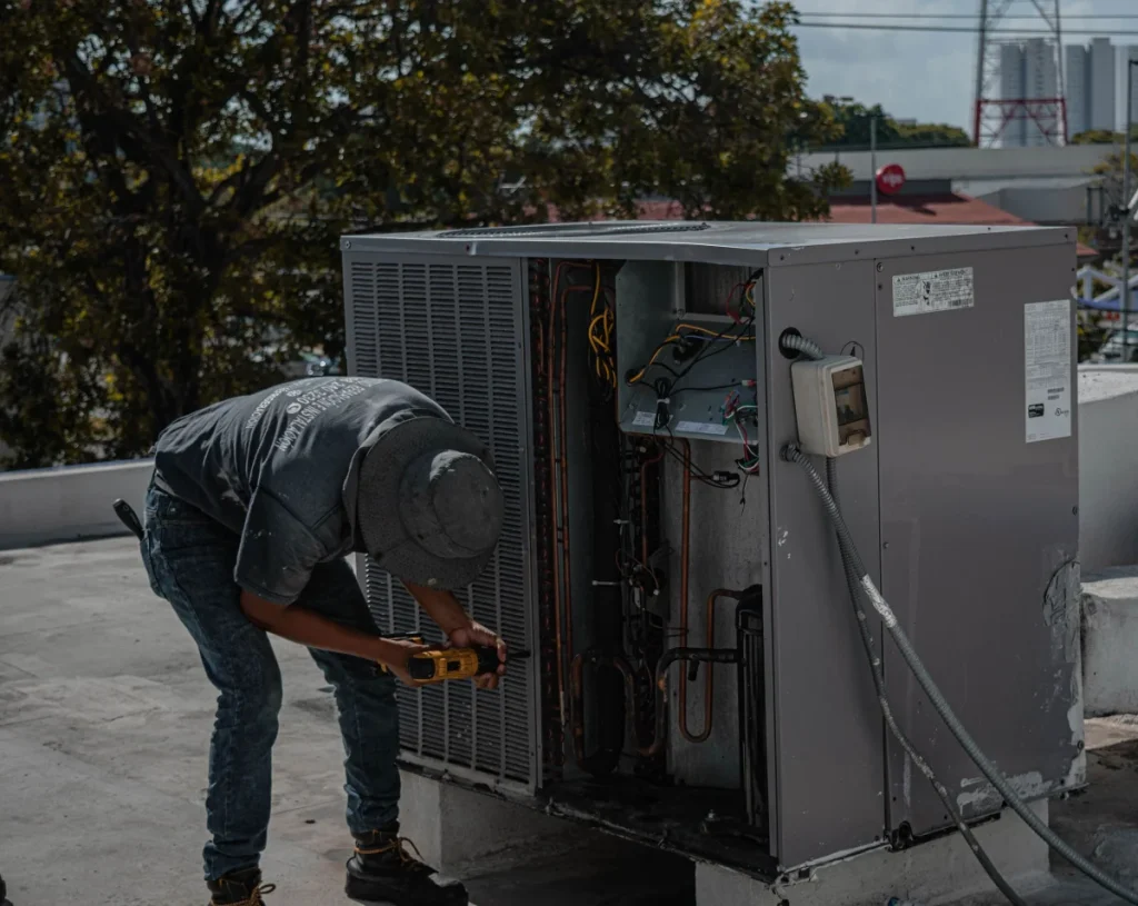 Technician servicing a rooftop package HVAC unit on a commercial building