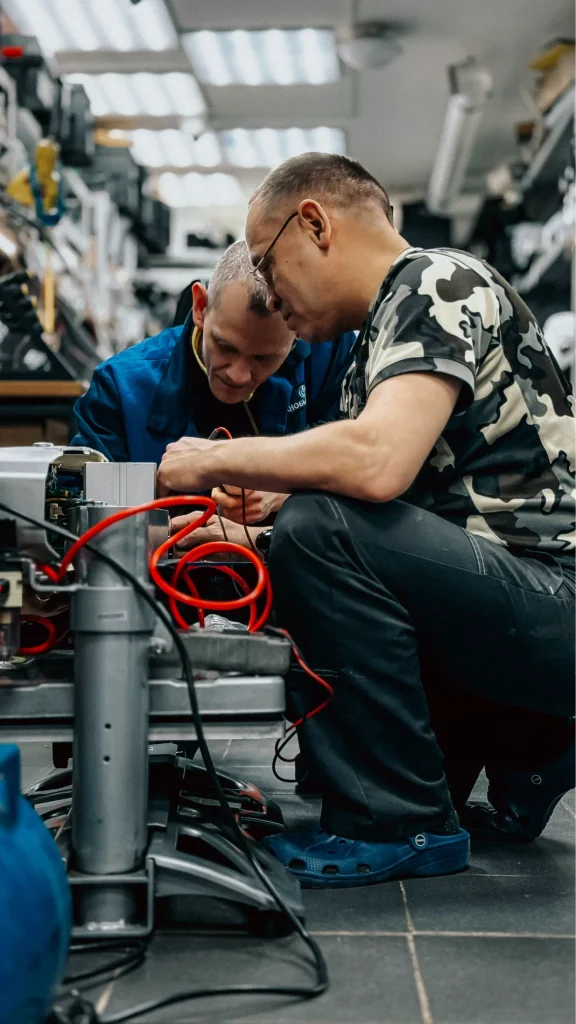 Two HVAC technicians working on equipment in a service workshop